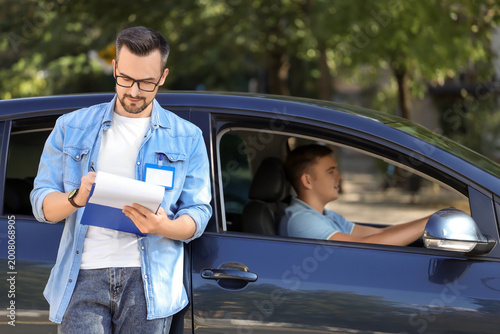 Fotografi Male instructor with examiner after passing driving license test outdoors