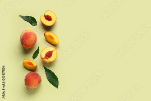 Obraz na płótnie Sweet ripe peaches and leaves on green background