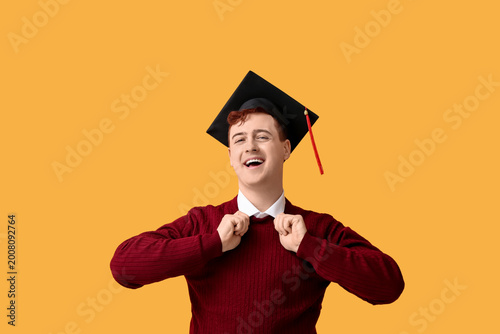 Male student in mortar board on yellow background