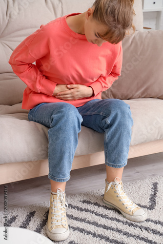 Quadro em tela Young woman suffering from stomach ache on sofa at home