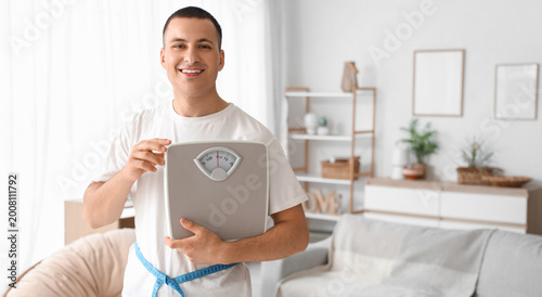 Young man with weight scales at home