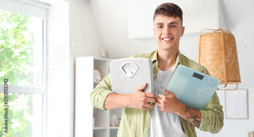 Young man with weight scales at home