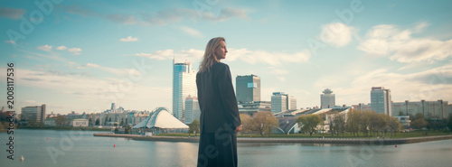 Confident business leader in full length suit overlooking metropolitan city with copy space