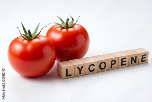 Two fresh red tomatoes with wooden blocks spelling lycopene, a healthy antioxidant nutrient