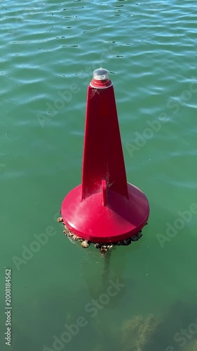 red buoy floating in the water,  used to define the edge of a navigable channel when returning from open water toward a harbor