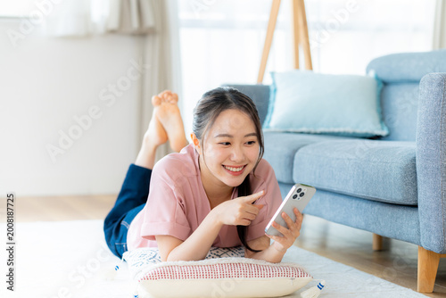 部屋でスマホを操作する若い女性