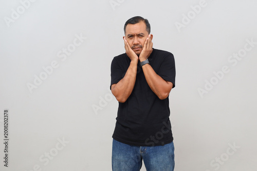 Fotografie Asian adult man standing isolated on white background, looking frustrated and covering ears