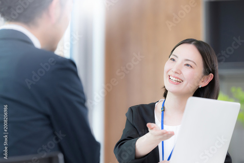 Photos 綺麗なオフィスで法人営業でヒアリングしながら提案(プレゼン)する若い女性社員のポートレート信頼と商談　保険や企画の提案などのイメージ