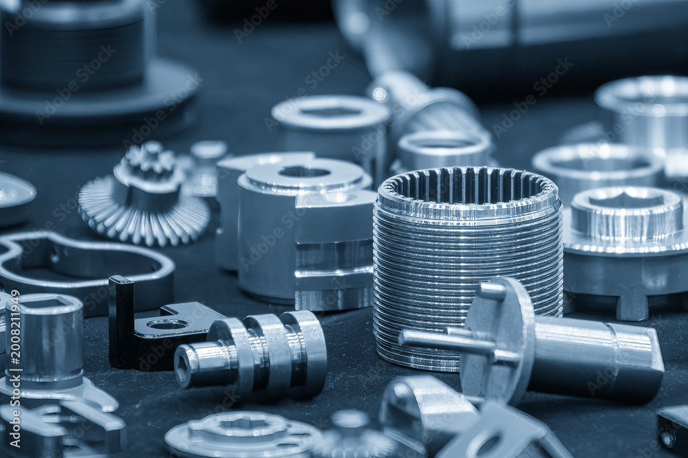 Naklejka premium Group of high precision metal parts and components manufactured by CNC lathe machine in a blue-toned industrial setting.