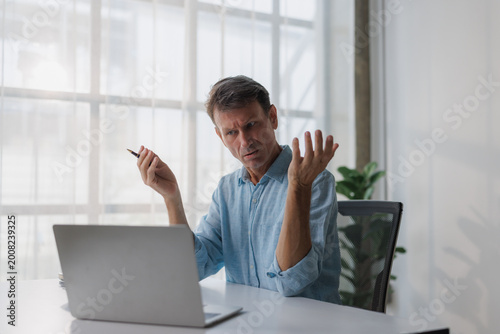 Mature man feeling confused while working with laptop