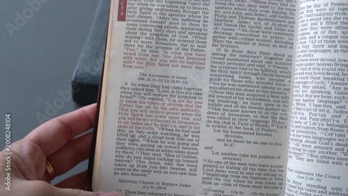 Holy Bible open up to the book of Acts of the new testament, zooming into Chapter 1 verse 8 on receiving power and being witnesses. New Revised Standard Versi