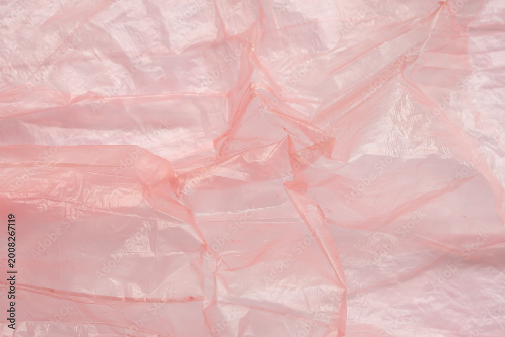Fototapeta premium Crumpled red plastic texture, wrinkled polyethylene bag surface background