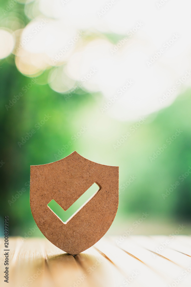 Behang Wooden shield icon with check mark on natural bokeh background