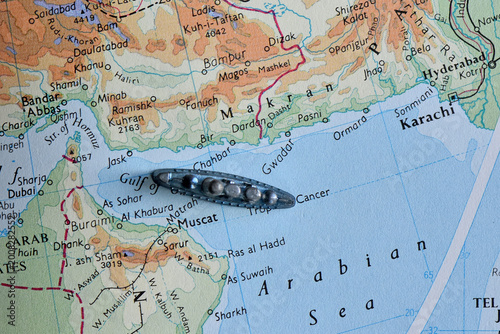 Obraz na płótnie Vintage map of the Arabian Sea and Gulf of Oman featuring a toy battleship near the coast of Muscat and Karachi, symbolizing naval strategy, maritime security, and regional geopolitics