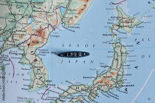 Fotografie Toy battleship on a vintage map of East Asia, placed in the Sea of Japan between Japan and the Korean Peninsula, symbolizing maritime travel, exploration, and naval military strategy