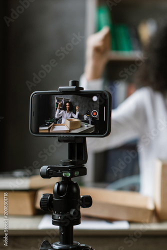 Tableau sur toile A woman excitedly records herself unboxing a package while filming with her smar