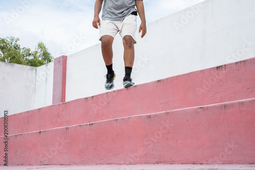 running up outdoor steps, Rear view of elderly man in sportswear running quickly up amphitheater stairs during everyday morning jogging at park against cloudy sky, copy space