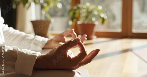 Person meditating in a sunlit room, surrounded by plants, promoting relaxation and mindfulness