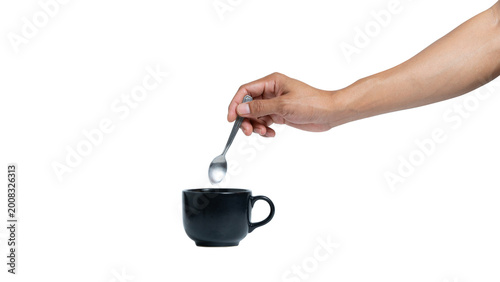 Man's hand holding a black ceramic coffee cup and stirring with a spoon isolated on white background. Professional gesture for morning routine or break time concept.