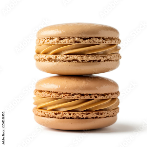 Two stacked caramel flavored french macarons with creamy filling on a plain white background