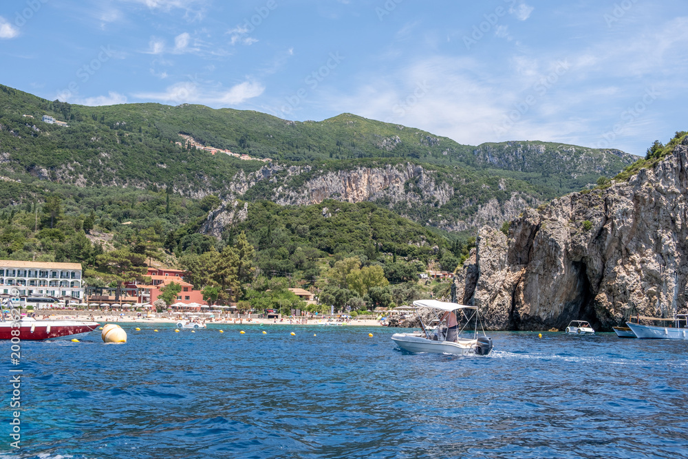Fototapeta premium Palaiokastritsa sandy beach, Corfu island, Greece. Seaside hotels, lush green hills, turquoise waters