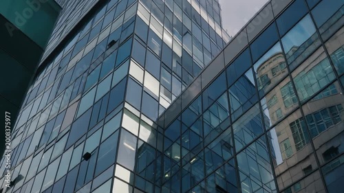 A close-up view of a modern glass building reflecting another structure in the city.