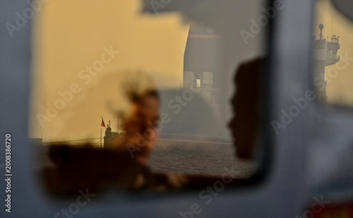 Dreamy Reflection of a Man and Woman on a Ferry Window with a Ship in the Background