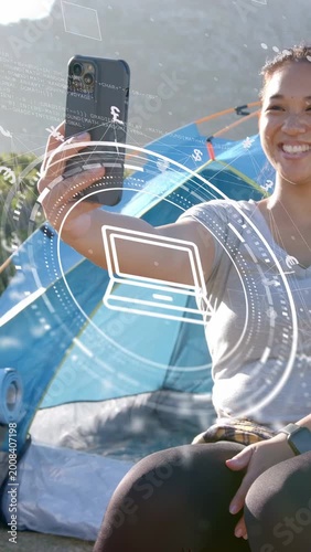 Vertical video: Camper raising phone starting AR fintech HUD showing money icons for managing funds
