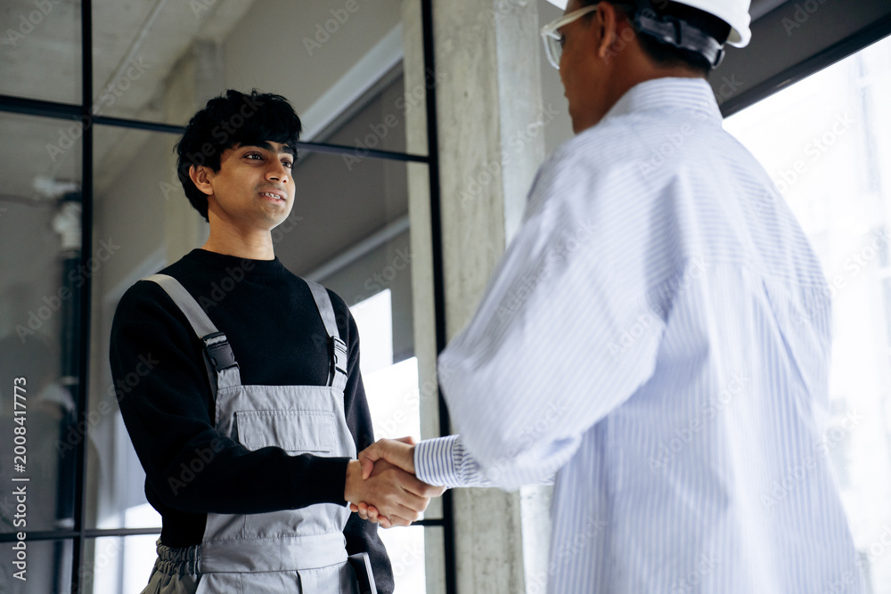 Obraz premium Construction worker and engineer shaking hands, finalizing a business deal on a building site. Teamwork, agreement and collaboration