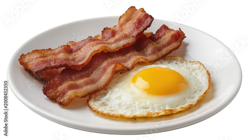 Photography Crispy bacon strips alongside sunny side up fried egg on plate