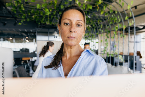 Confident woman demonstrating leadership in open office environment