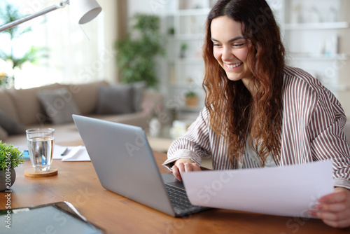 Happy young teleworker working at home checking laptop