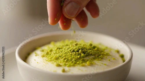 Sprinkling Chopped Pistachios on a Creamy Dessert.