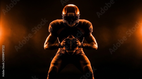 American football player holding ball in dark stadium with dramatic lighting effects