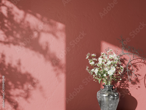 Muted red wall with white flowers in a vase and artistic tree branch shadows.