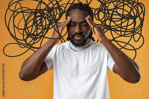 Принти на полотні Person holds head with hands in front of orange wall while looking stressed from