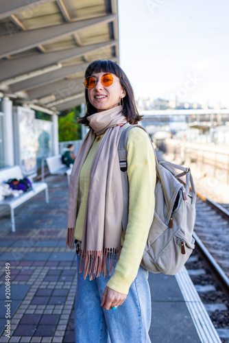 A passenger is waiting for a train. A stylish young woman is waiting for a train on the platform.