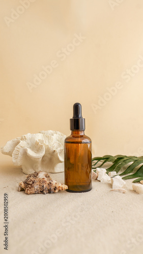 Foto Amber glass dropper bottle with natural elements on sandy beach background