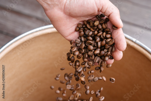 Person Pouring Freshly High Detailed Roasted Coffee Beans into Industrial Storage Drum