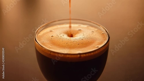 Close Up of Rich Espresso Coffee Pouring into a Clear Glass with Crema.