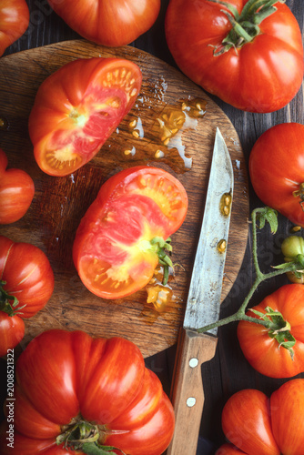 Cut heirloom tomato on wooden board with visible seeds and pulp. Fresh organic vegetable detail, healthy food preparation