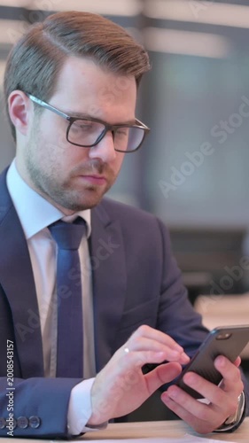 Businessman Browsing Internet on Smartphone in Office