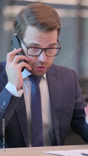 Angry Businessman Talking on Phone in Office