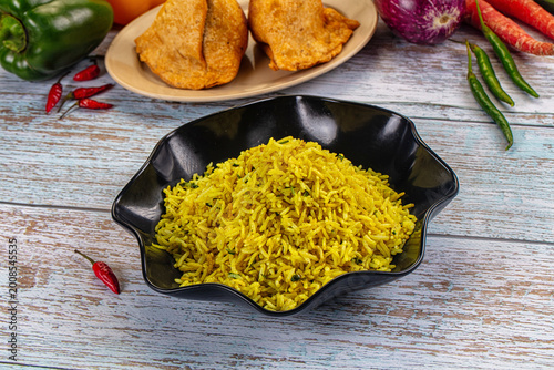 Photos Bowl of yellow basmati rice pilaf with herbs, served with appetizers on a rustic wooden table
