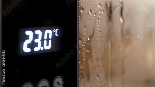 Digital display showing 22.5 degrees Celsius with condensation on glass indicating temperature monitoring and technology in a close-up shot