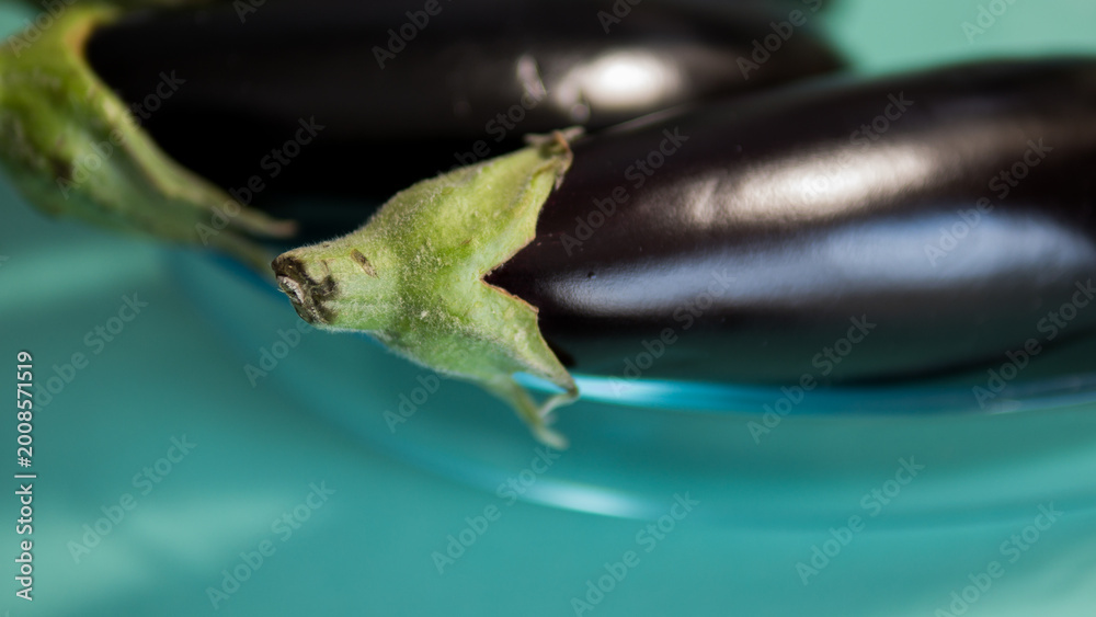 Naklejka premium Fresh eggplants in glass bowl close up organic vegetables cooking concept