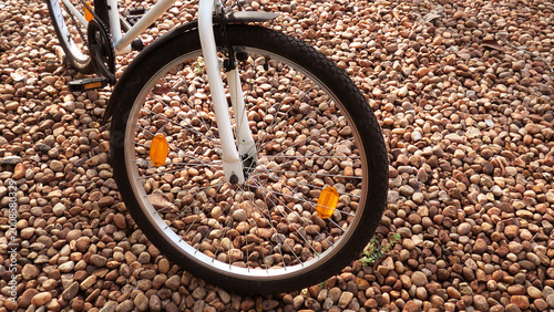 Closeup of the wheels of a bicycle parked on the ground paved with pebbles