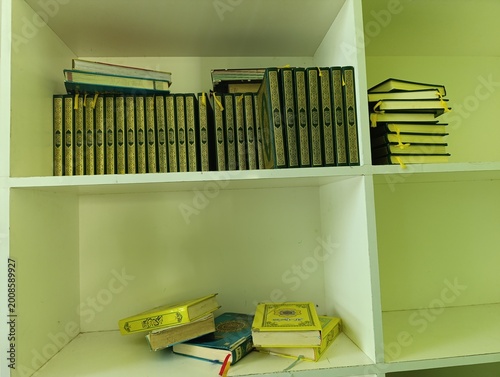 Holy Quran books arranged on white shelves in an Islamic library