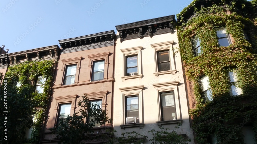 Fototapeta premium New York City townhouse buildings, brownstone row houses in Manhattan or Brooklyn, United States of America. Classic buildings on residential district street. Real estate property. Rowhouse townhome.