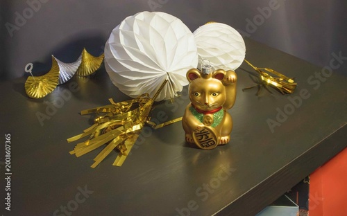 Decorative items in oriental style on table with a golden lucky cat figurine and paper ornaments
